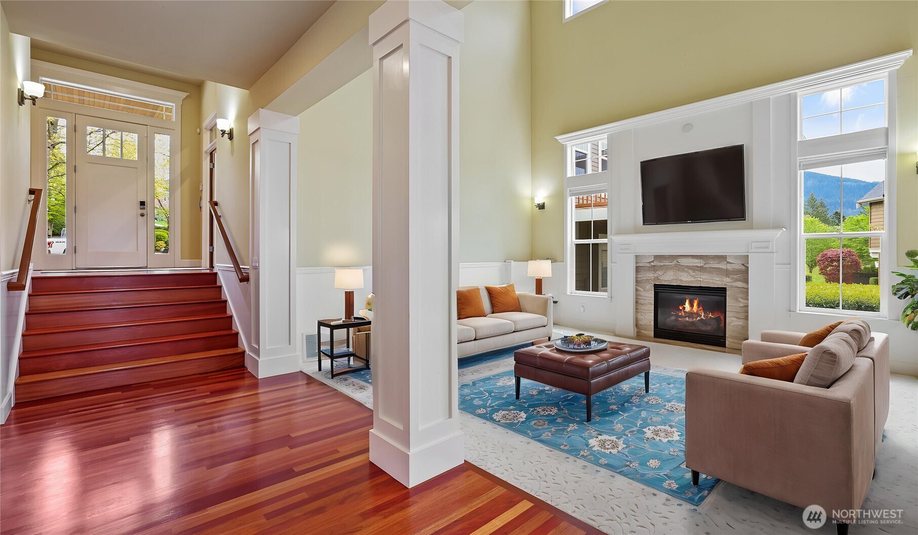 A show stopping living room with sky-high ceilings, wainscoting, ceiling fan and a statement fireplace centerpiece. *Virtually Staged*