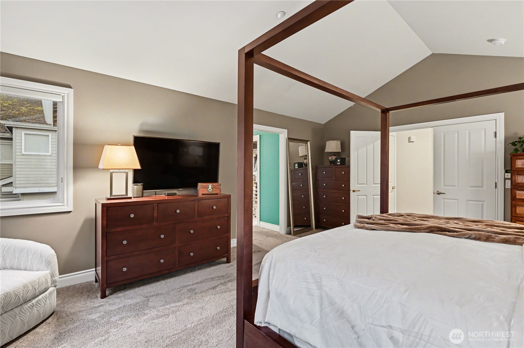 Primary bedroom features double door entry, vaulted ceilings and large windows.