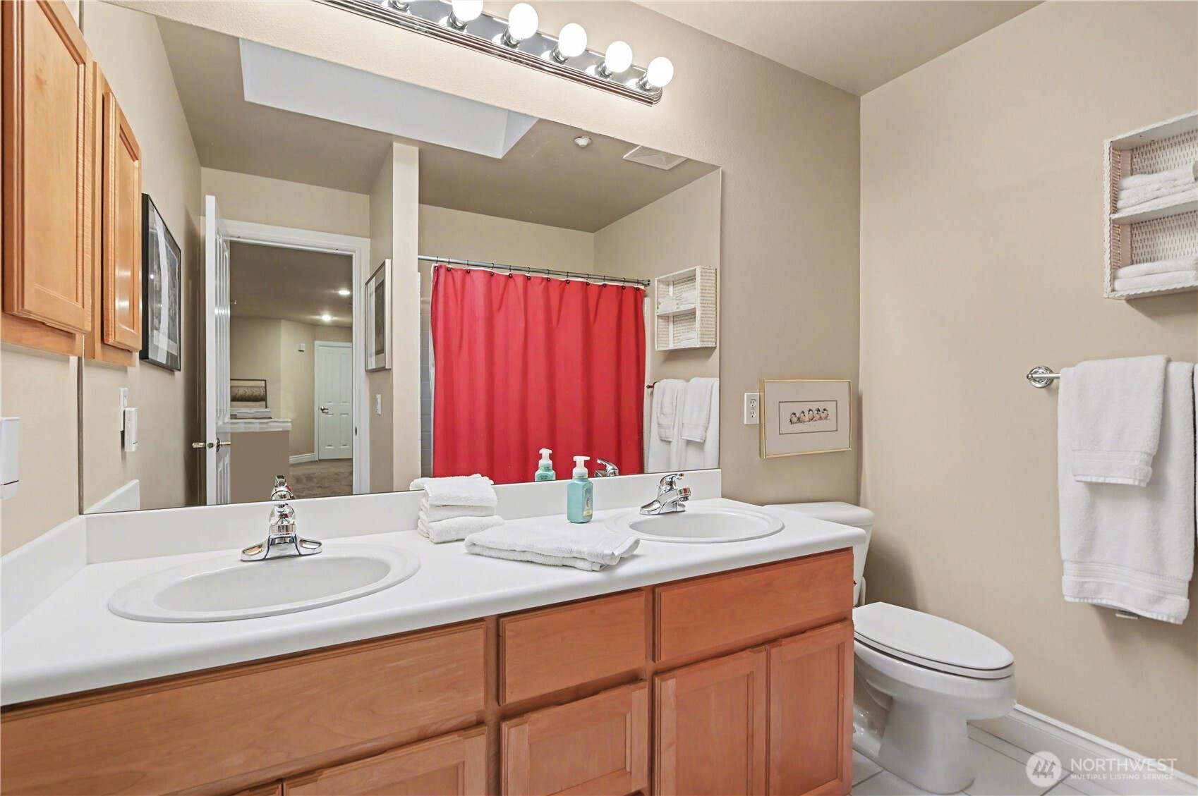 Full upstairs bathroom offers dual vanity and natural light from a skylight.