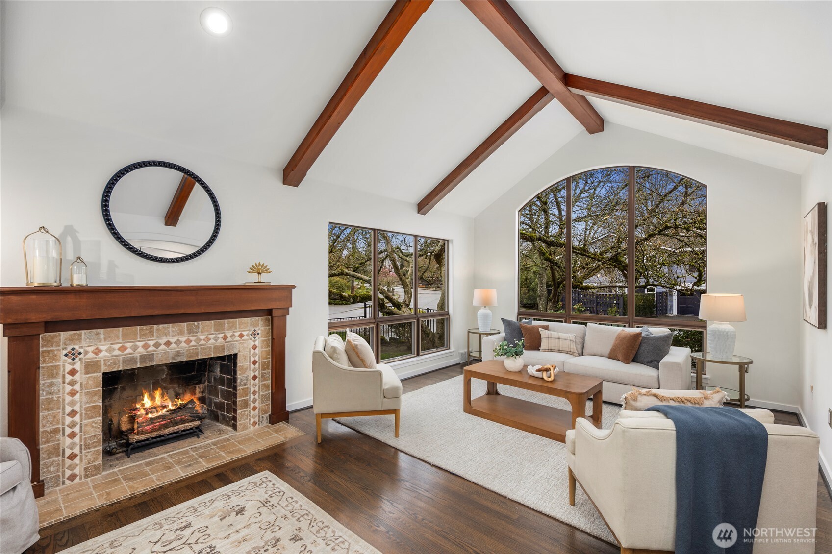 The living room impresses with soaring vaulted ceilings, exposed wood beams, and expansive picture windows that fill the space with natural light.