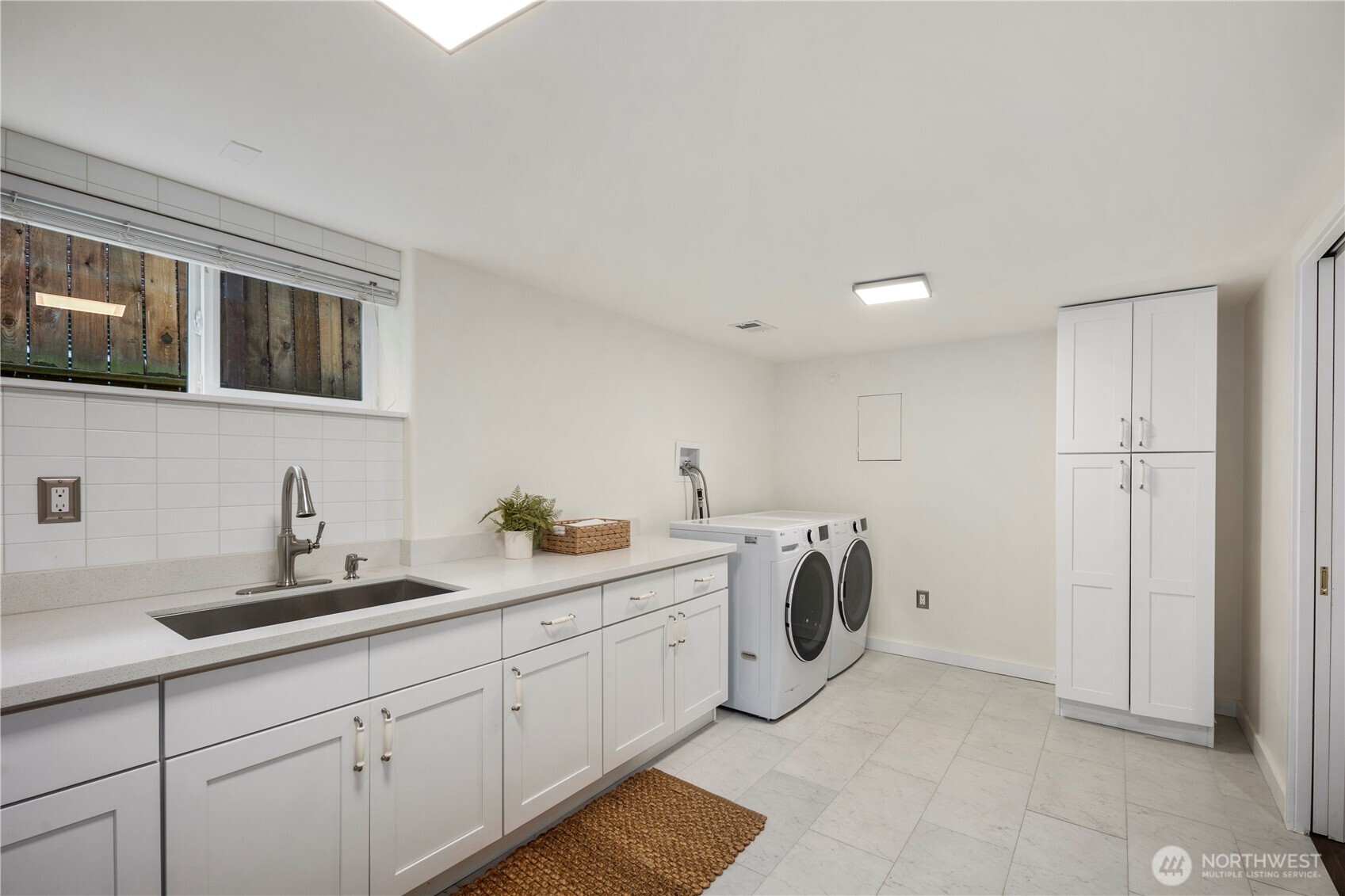 Large laundry room featuring a generous folding counter and utility sink, making everyday tasks both functional and efficient.
