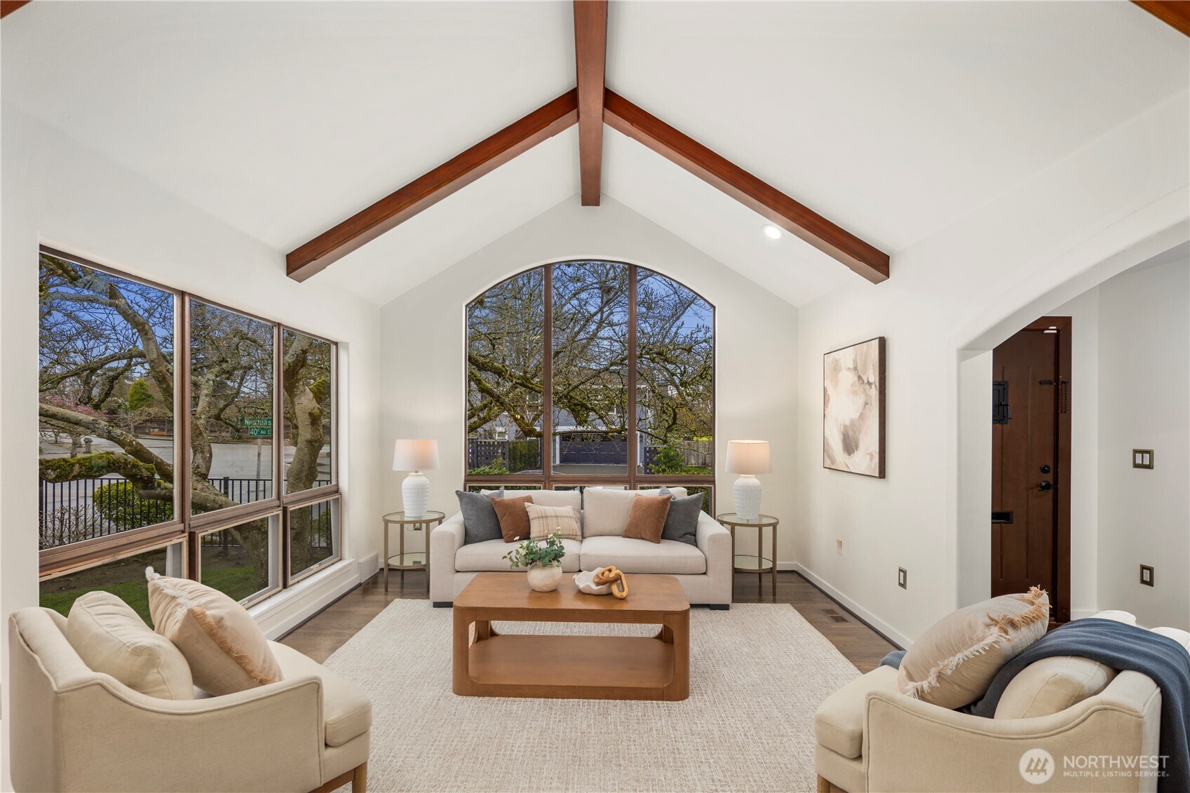 The living room impresses with soaring vaulted ceilings, exposed wood beams, and expansive picture windows that fill the space with natural light.
