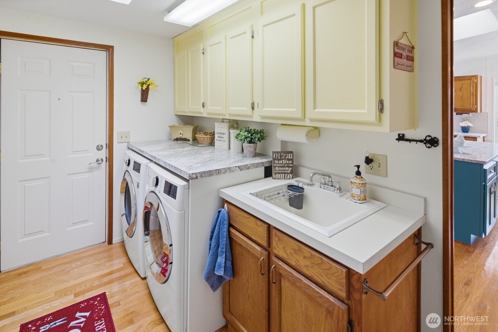 Spacious laundry room with full-size washer and dryer, cabinet storage, and laundry sink