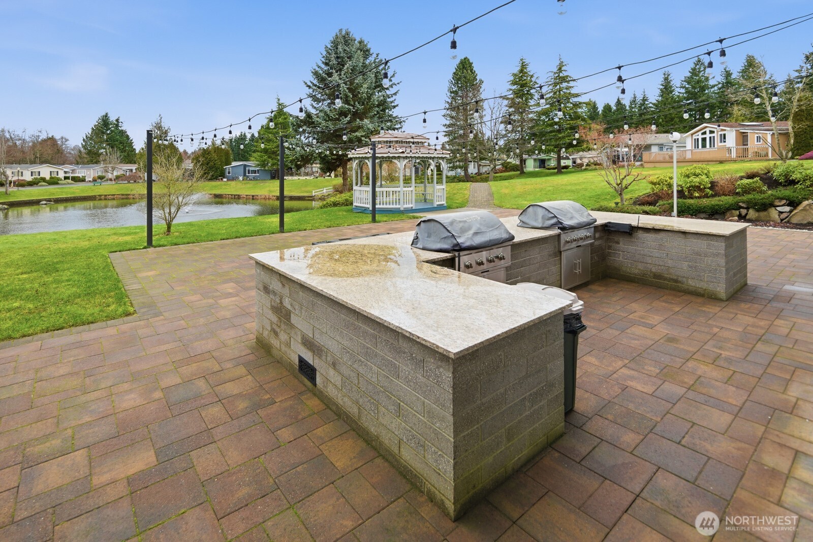 Outdoor entertaining area with grill, gazebo, water feature, and walking paths