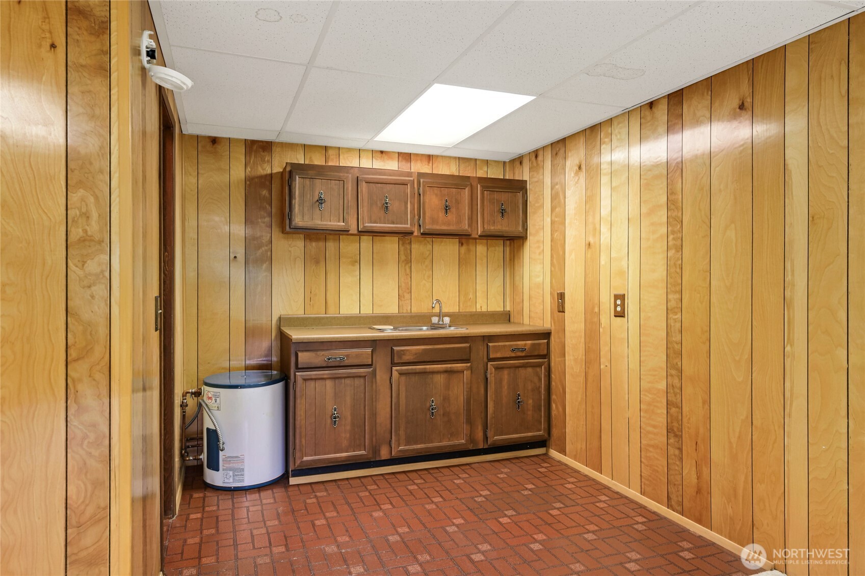 Kitchenette with sink, counter space and cabinets.  Real wood panel walls.