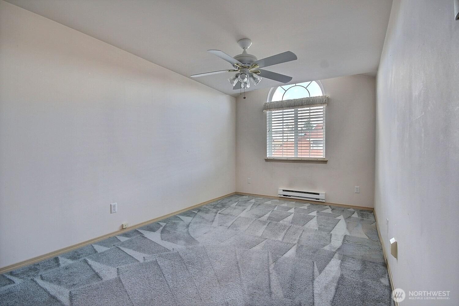 Second bedroom on the upper level features a decorative arched transom window for maximum light, newer baseboard heater and an overhead ceiling fan/light.