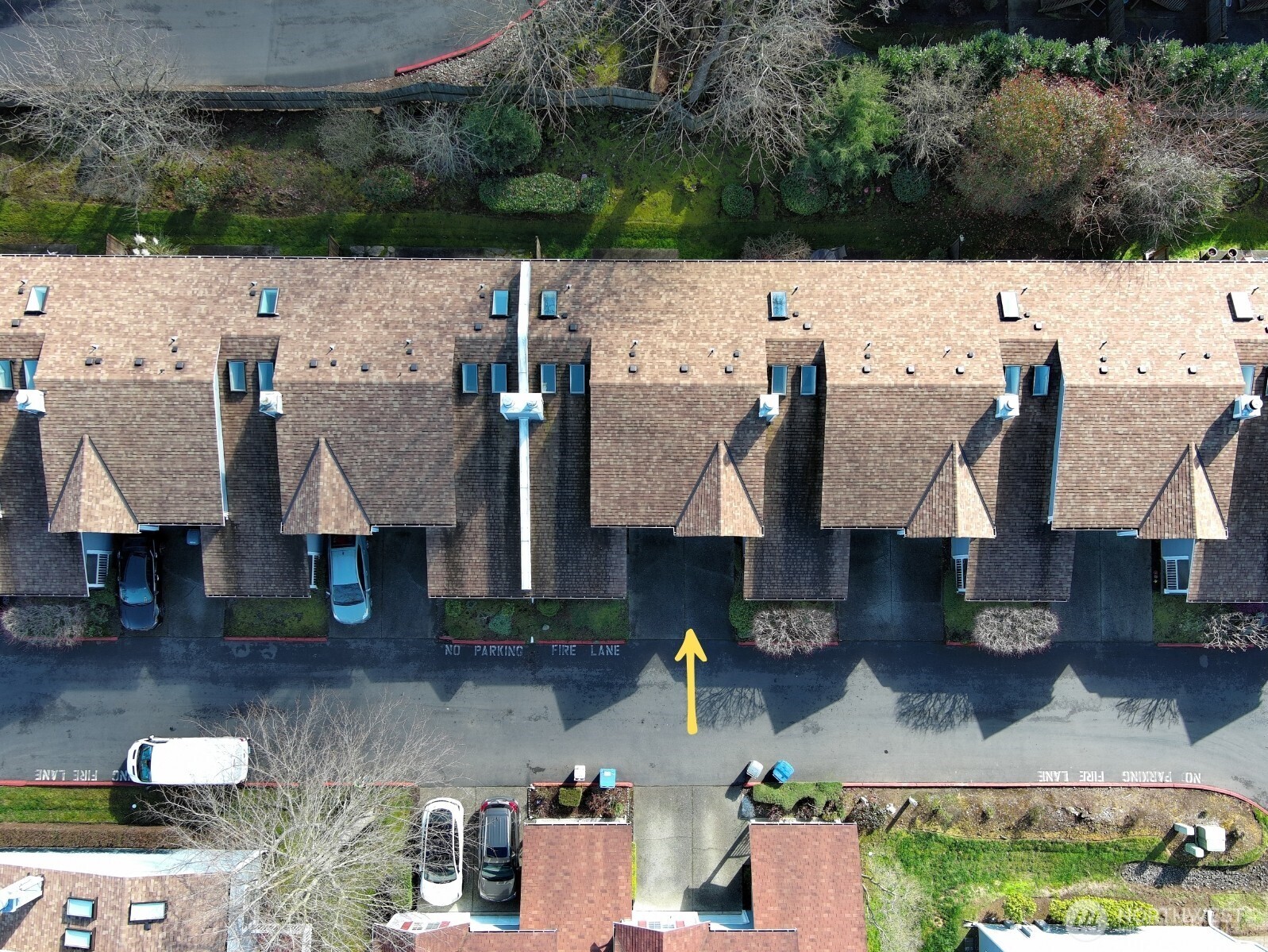 This aerial shot looks down upon the backyard area where mature trees and soft mossy green space create a quiet, park-like sanctuary right behind your home.