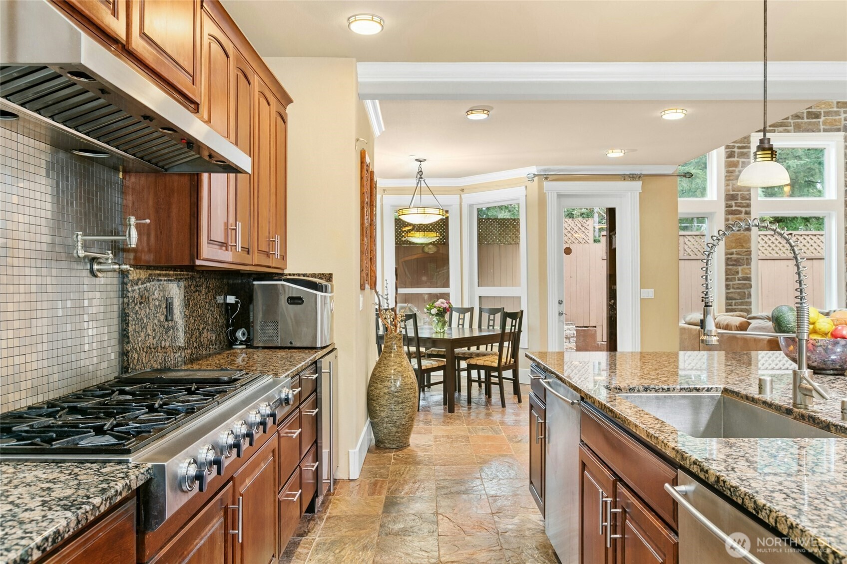 Chef’s kitchen featuring a Jen air 6-burner range with griddle, built-in GE Monogram refrigerator, wall oven and microwave, two Bosch dishwashers, beverage refrigerator, pot filler, and a built-in desk area.