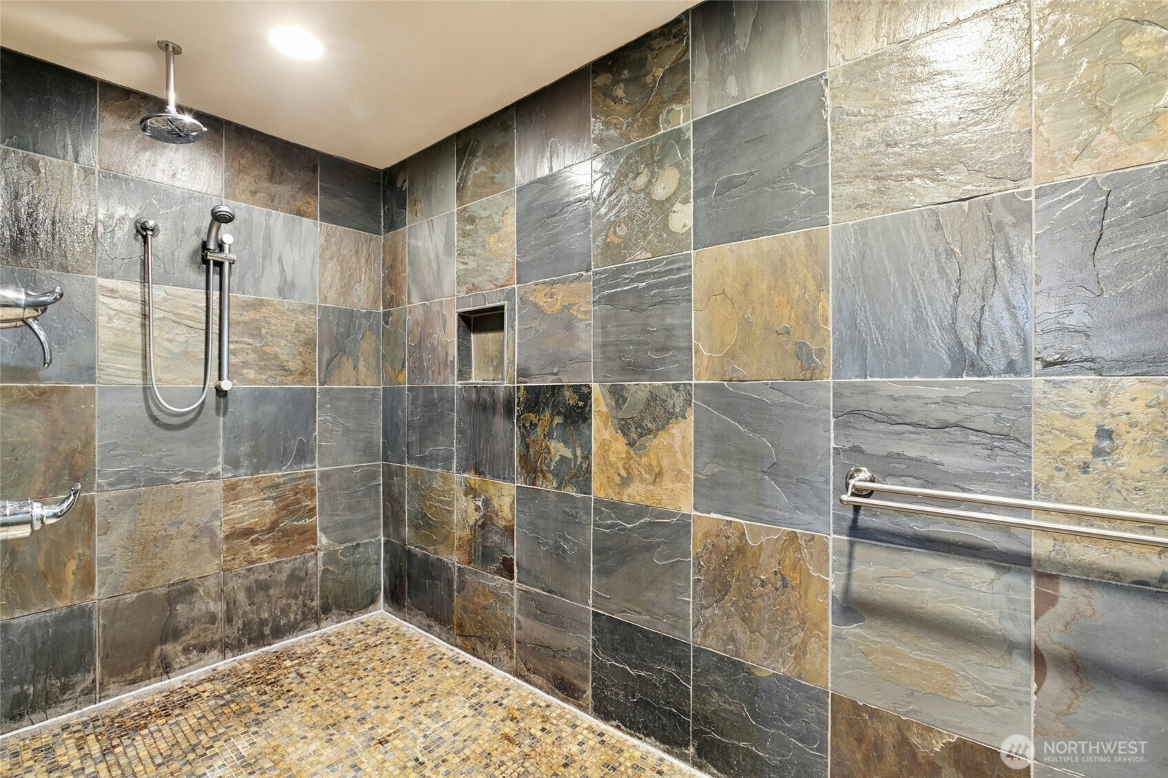 Elegant spa-style primary bath showcasing a 7-function body spray system and impressive custom stone craftsmanship.