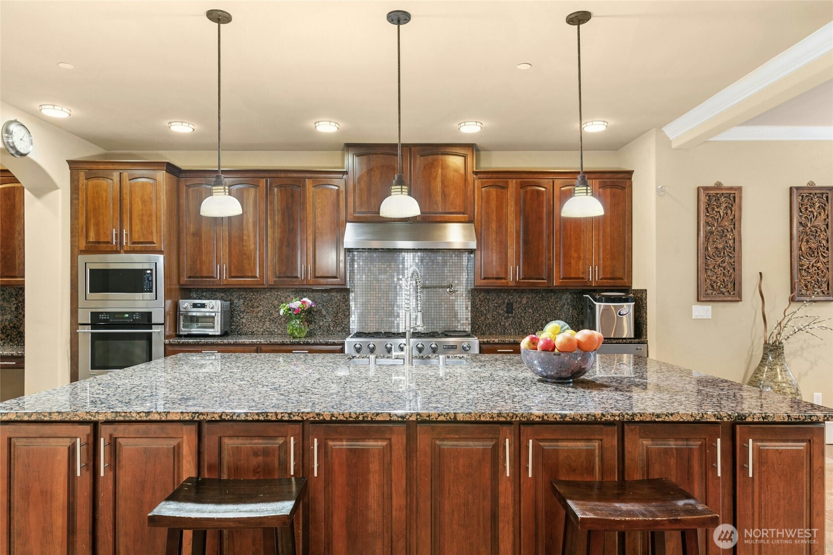 Chef’s kitchen featuring a Jen air 6-burner range with griddle, built-in GE Monogram refrigerator, wall oven and microwave, two Bosch dishwashers, beverage refrigerator, pot filler, and a built-in desk area.