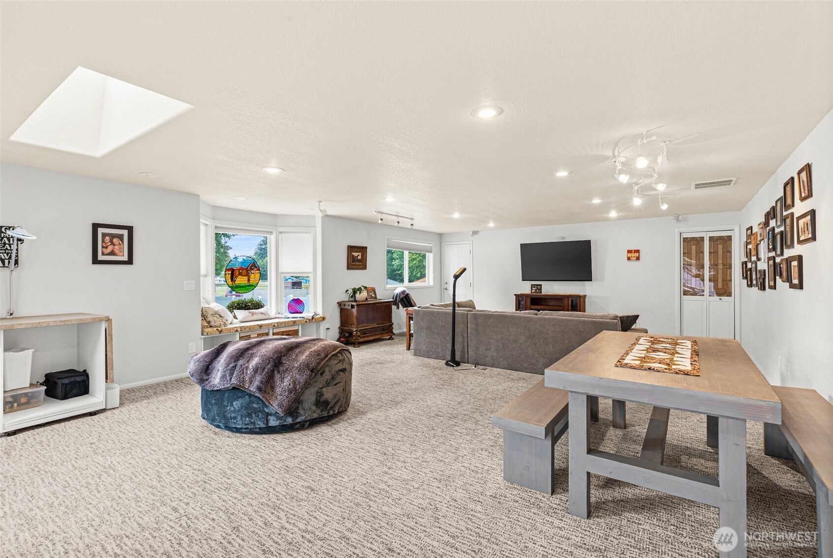 This large gathering media room is perfect for movie nights, gaming, and crafting activities, offering a versatile space for family and friends. A bay window fills the room with natural light and provides a cozy nook for reading or relaxing, while a skylight enhances the airy, open feel. A sliding glass door opens to a deck, ideal for outdoor lounging, and a nearby door leads directly to the inground pool area, creating easy access for poolside fun and entertainment. The room's layout makes it a great hub for both indoor and outdoor activities.            This large gathering media room is perfect for movie nights, gaming, and crafting activities, offering a versatile space for family and friends. A bay window fills the room with natural light and provides a cozy nook for reading or relaxing, while a skylight enhances the airy, open feel. A sliding glass door opens to a deck, ideal for outdoor lounging, and a nearby door leads directly to the inground pool area.