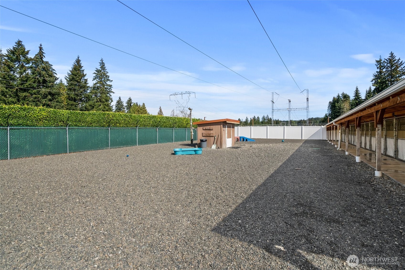 Outdoor play area features durable gravel flooring, designed for easy maintenance and cleanliness, while offering a safe and comfortable surface for pets to play and explore. Fully fenced, ensuring a secure environment.