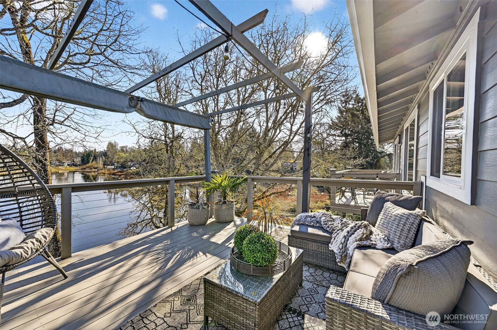 Covered lakefront deck with built-in hot tub and rail views, perfect for year-round outdoor living.