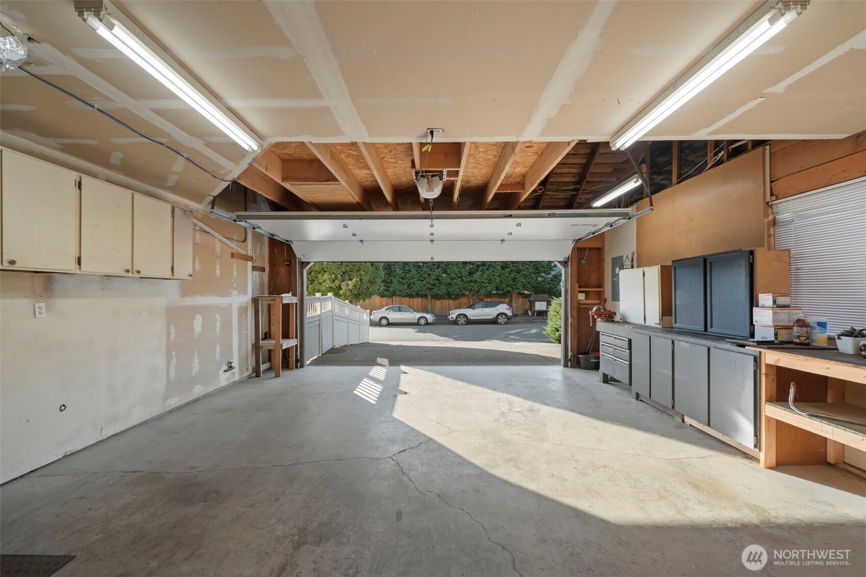 Rear exterior of the home featuring a large deck, patio seating area, and generous yard framed by mature landscaping.
