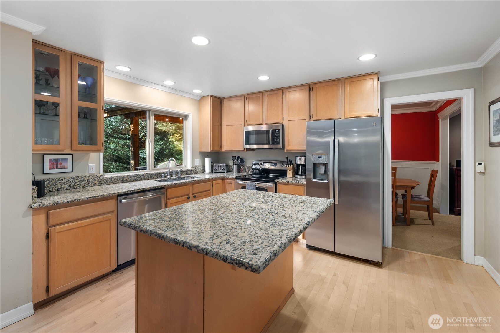 Sun-drenched open-concept dining area with views of the private, wooded yard through expansive windows.
