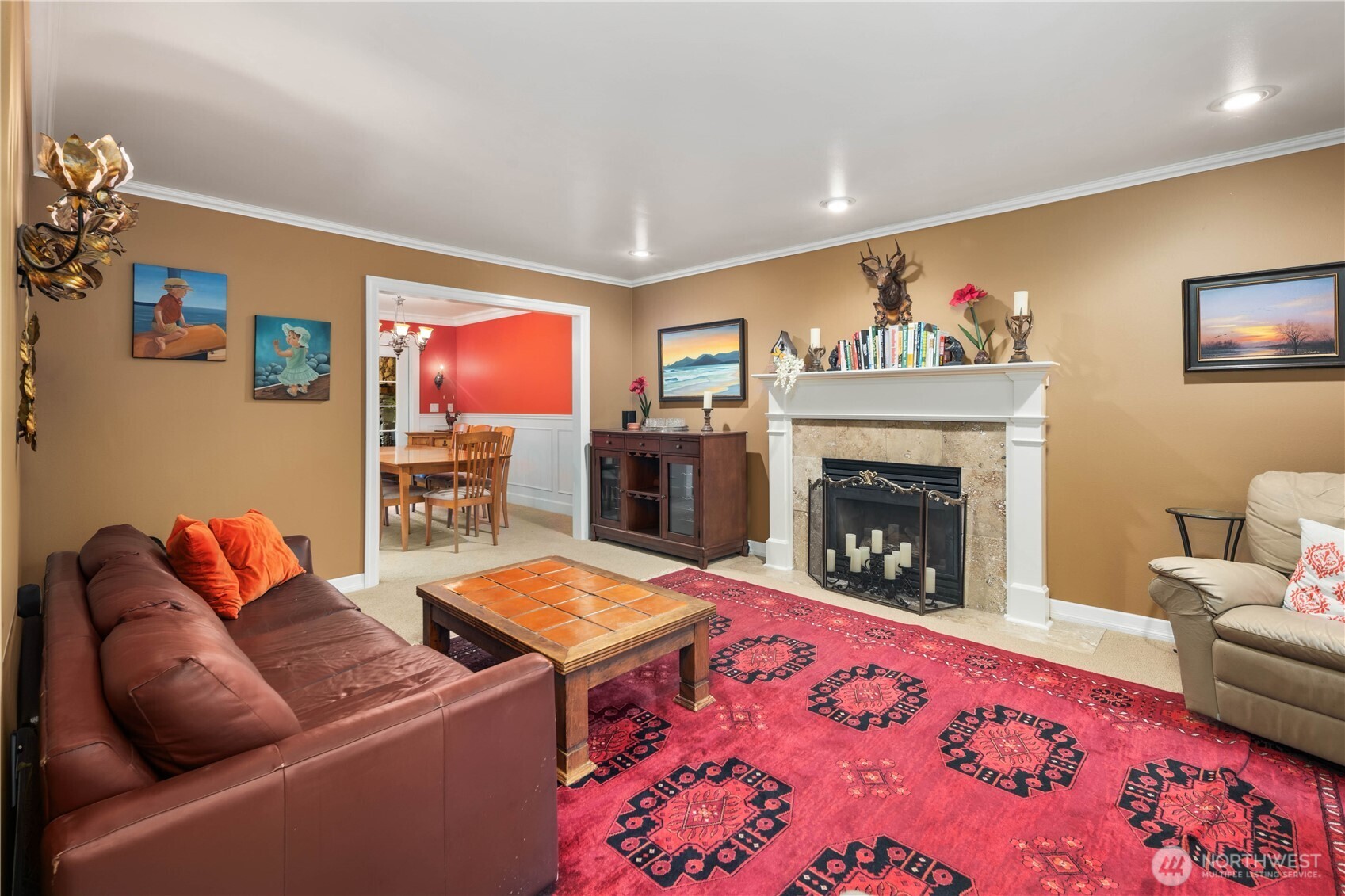 Cozy living room anchored by a classic white mantel fireplace and large windows for natural light.