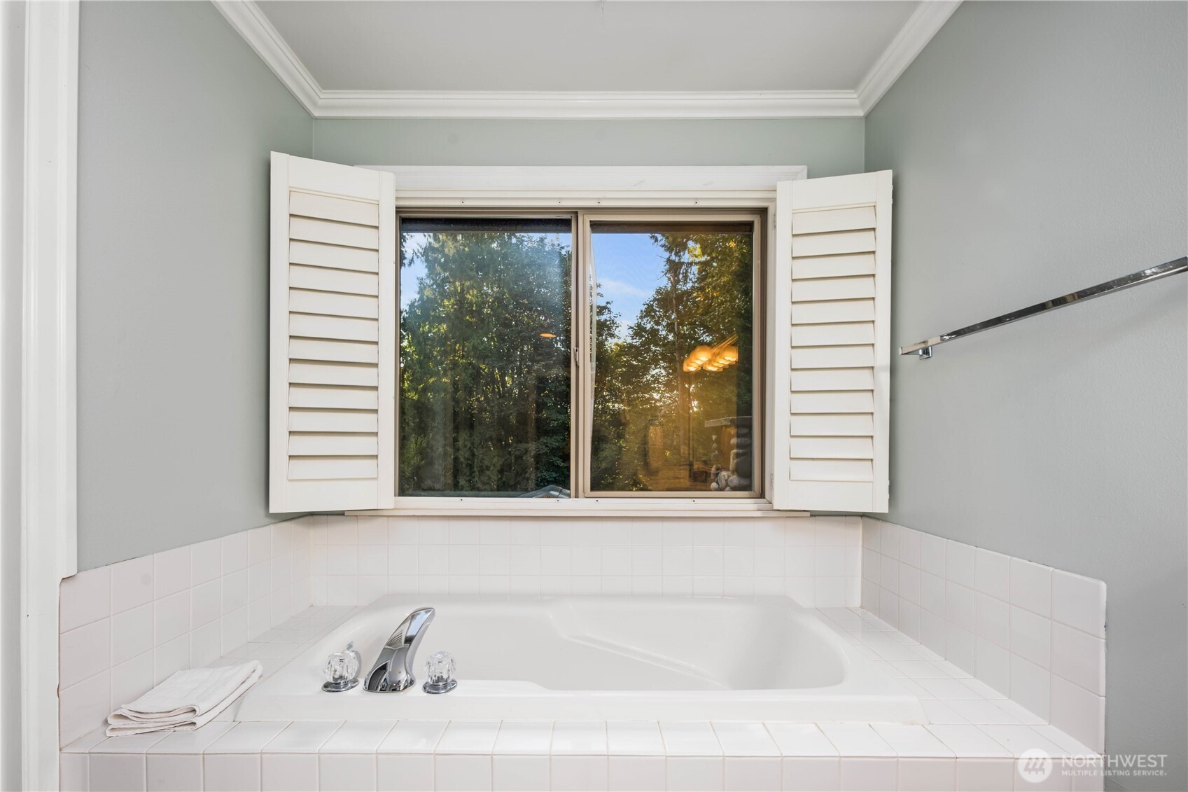 Bright and airy second bedroom with a ceiling fan and peaceful views of the surrounding trees.