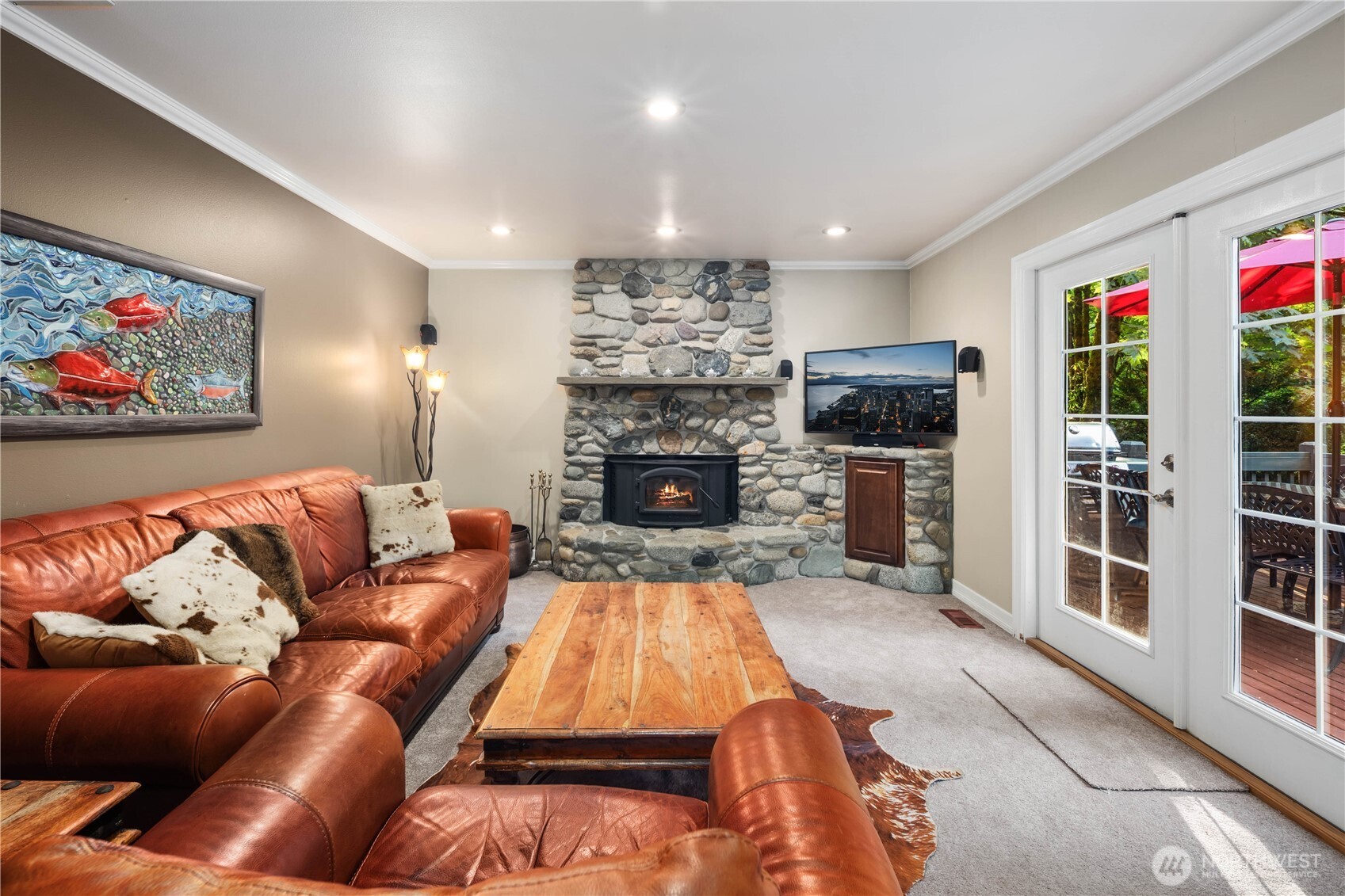 Inviting lower-level living area anchored by a rustic stone fireplace and direct outdoor access.