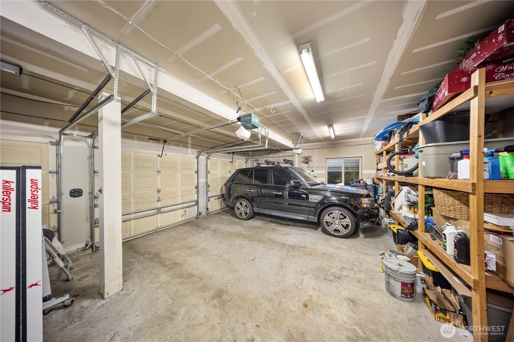 Spacious three-car garage equipped with built-in shelving and plenty of room for a workshop or storage.