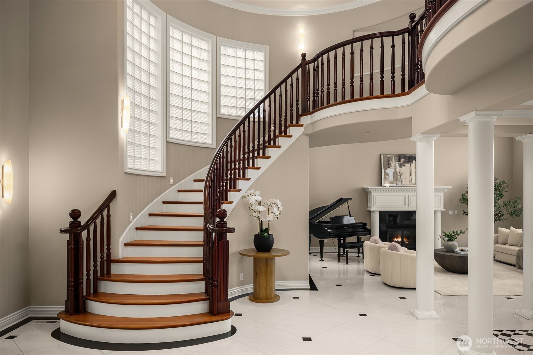 Grand entry foyer with sweeping curved staircase and soaring ceilings.