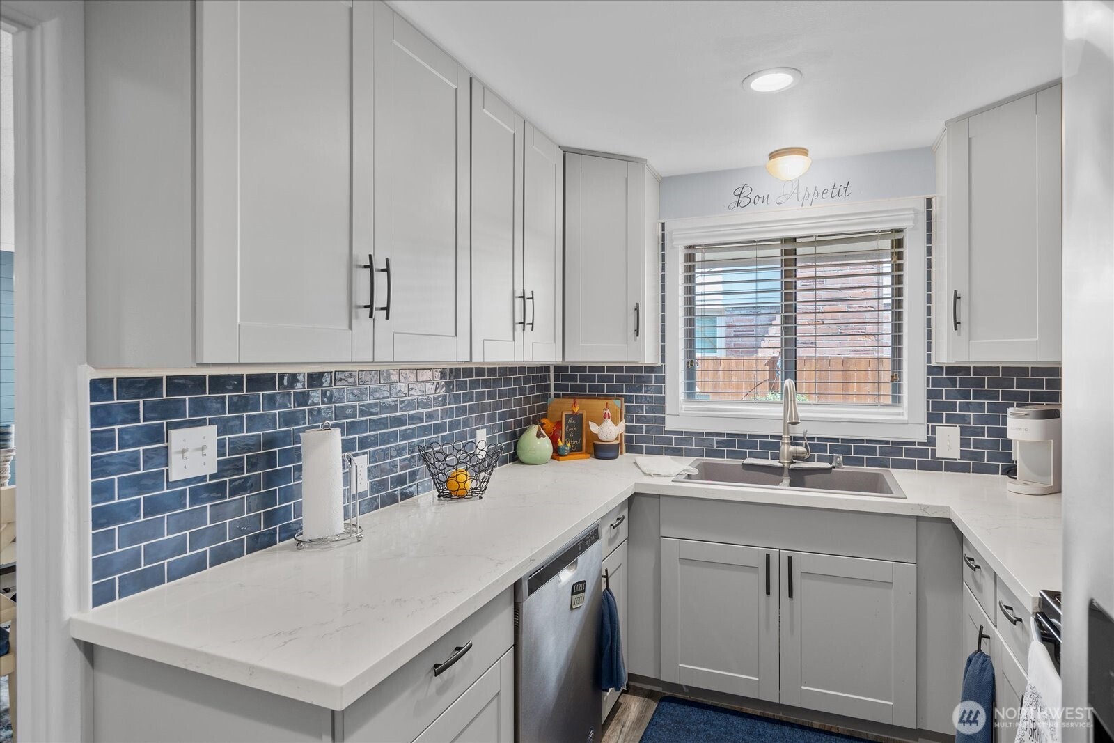 Remodeled kitchen featuring quartz countertops, shaker cabinetry, and a striking navy tile backsplash.