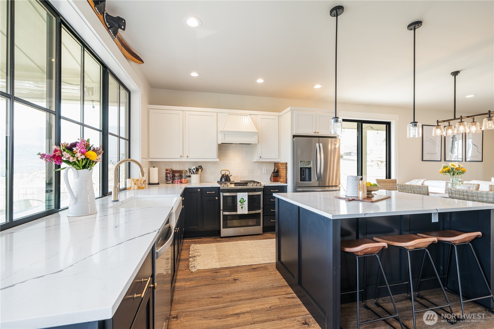 Kitchen with quartz countertops, engineered wood flooring, stainless steel appliances, sit up bar and French doors leaded to the view balcony and outdoor living space with BBQ and dining and lounge areas.