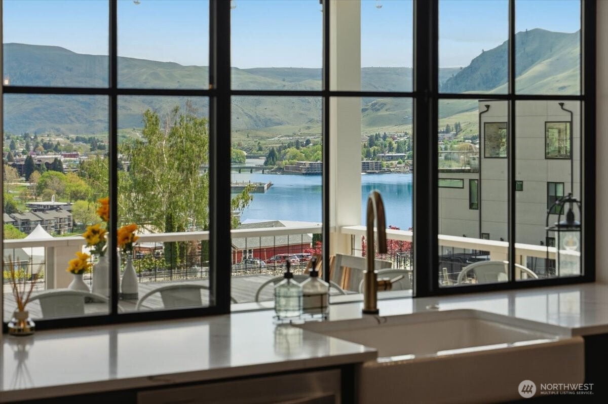 Detail view of kitchen with quartz countertops, farmhouse sink and upgraded black trimmed windows overlooking the lake and vineyard view deck and outdoor living area.