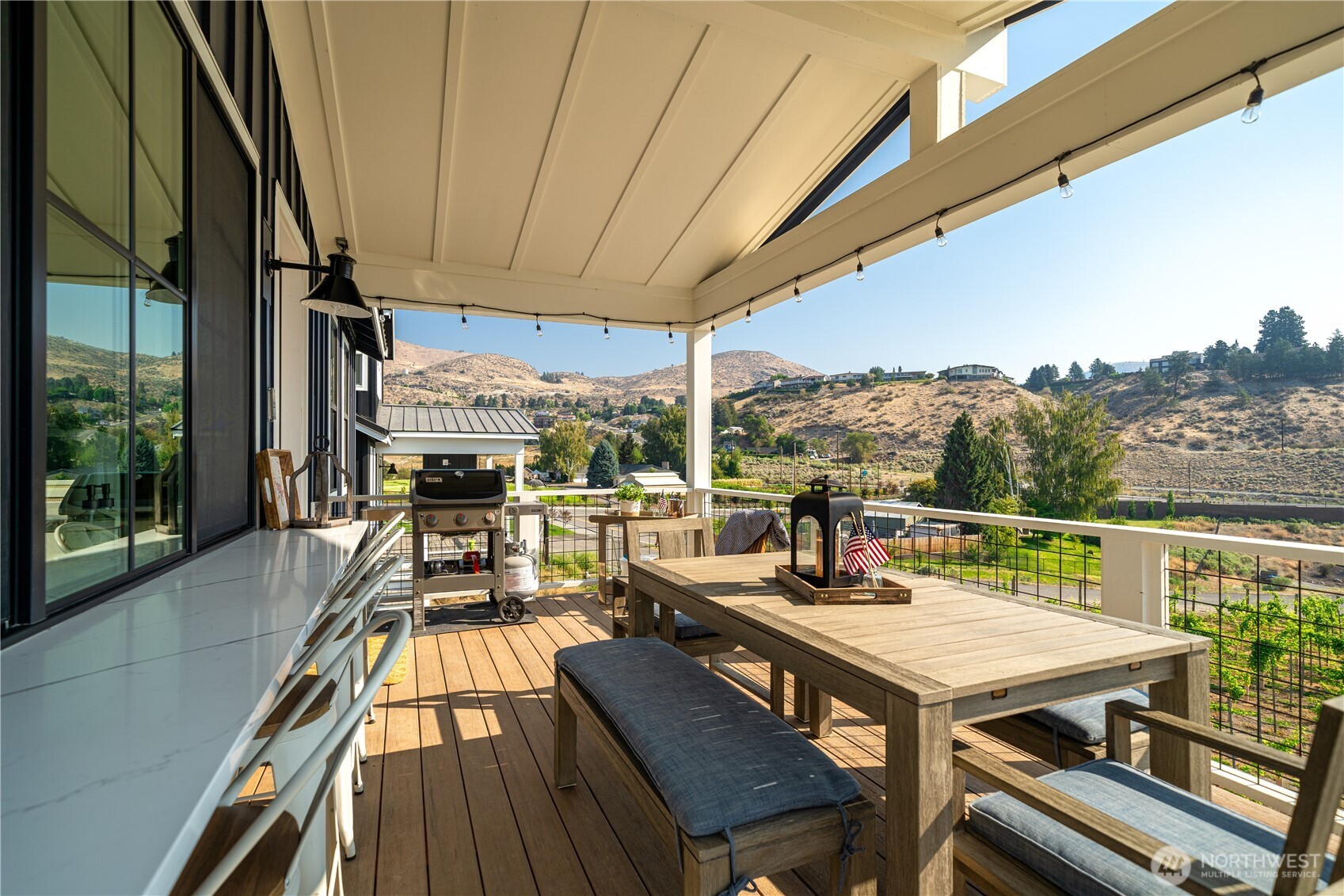 Main level outdoor living area with sit up bar with quartz countertops, dining table and views overlooking the Vin du Lac vineyards.