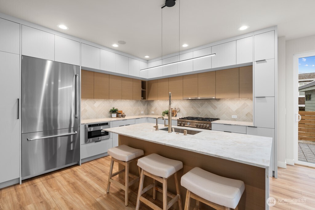 Bertazzoni suite of appliances, in-ceiling speakers, minimalist range hood, undercabinet lighting and tonal herringbone backsplash to set the mood
