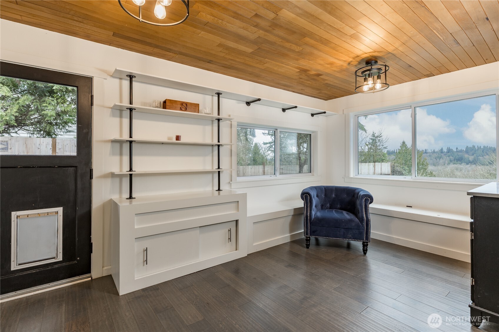 Architectural interest at every turn: this custom flex room boasts industrial-chic shelving, built-in storage benches, and warm wood ceiling accents