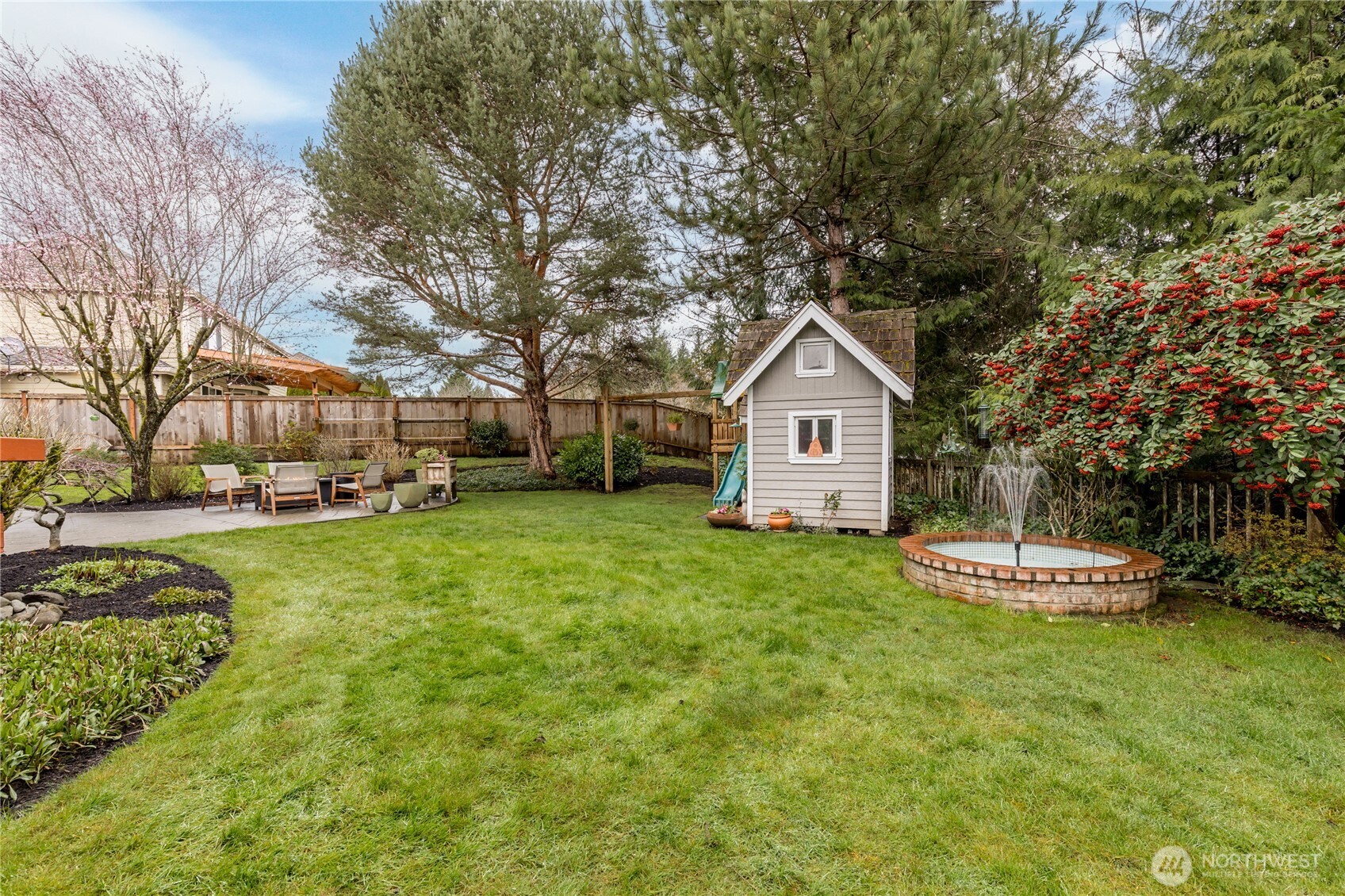 Level fully-fenced yard includes beautiful mature landscaping and a serene fountain