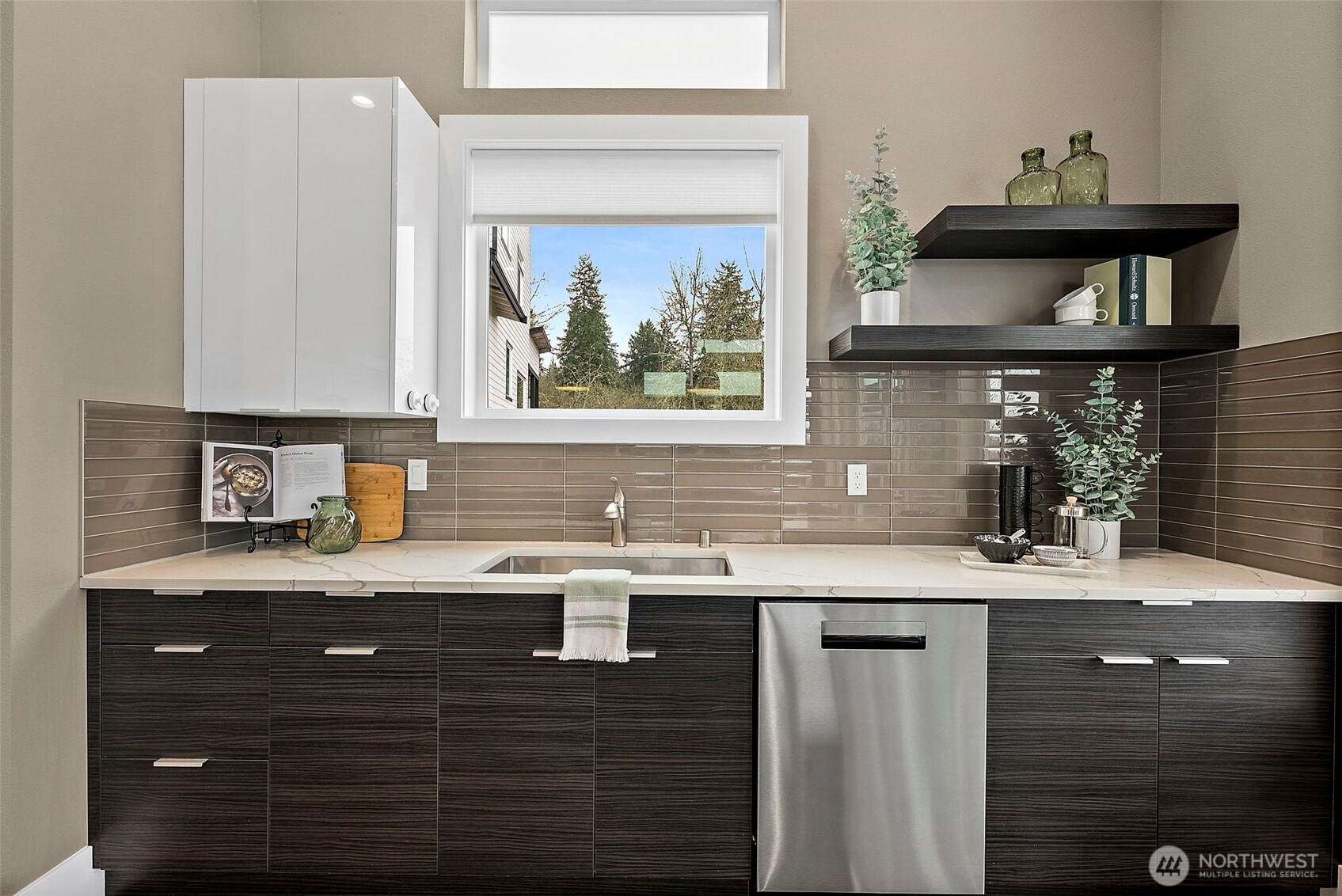 Modern kitchen in a home for sale in the River Rock community, featuring a large center island with seating, quartz countertops, stainless steel appliances, and sleek cabinetry. The open layout, abundant natural light, and connection to the living area create an ideal space for cooking, gathering, and everyday living.