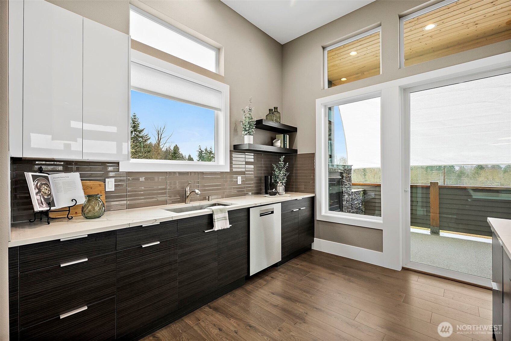Modern kitchen in a home for sale in the River Rock community, featuring a large center island with seating, quartz countertops, stainless steel appliances, and sleek cabinetry. The open layout, abundant natural light, and connection to the living area create an ideal space for cooking, gathering, and everyday living.