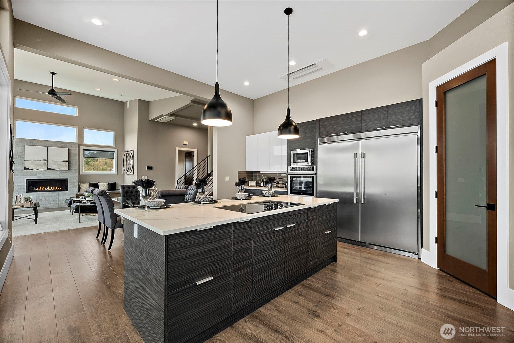 Modern kitchen in a home for sale in the River Rock community, featuring a large center island with seating, quartz countertops, stainless steel appliances, and sleek cabinetry. The open layout, abundant natural light, and connection to the living area create an ideal space for cooking, gathering, and everyday living.