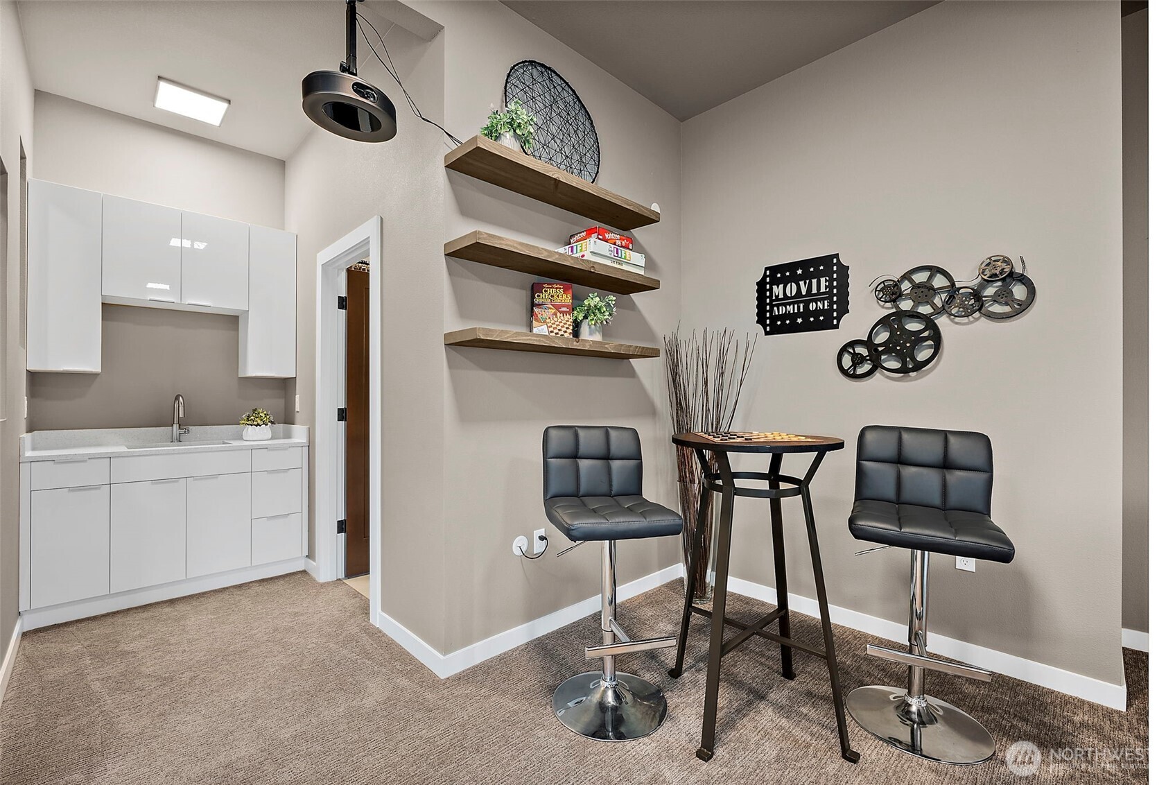 Spacious lower level entertainment room in this River Rock home in Auburn featuring a projector, large screen, wet bar, and comfortable seating areas. With direct patio access, this versatile rec room is designed for movie nights, hosting guests, and seamless indoor outdoor entertaining.