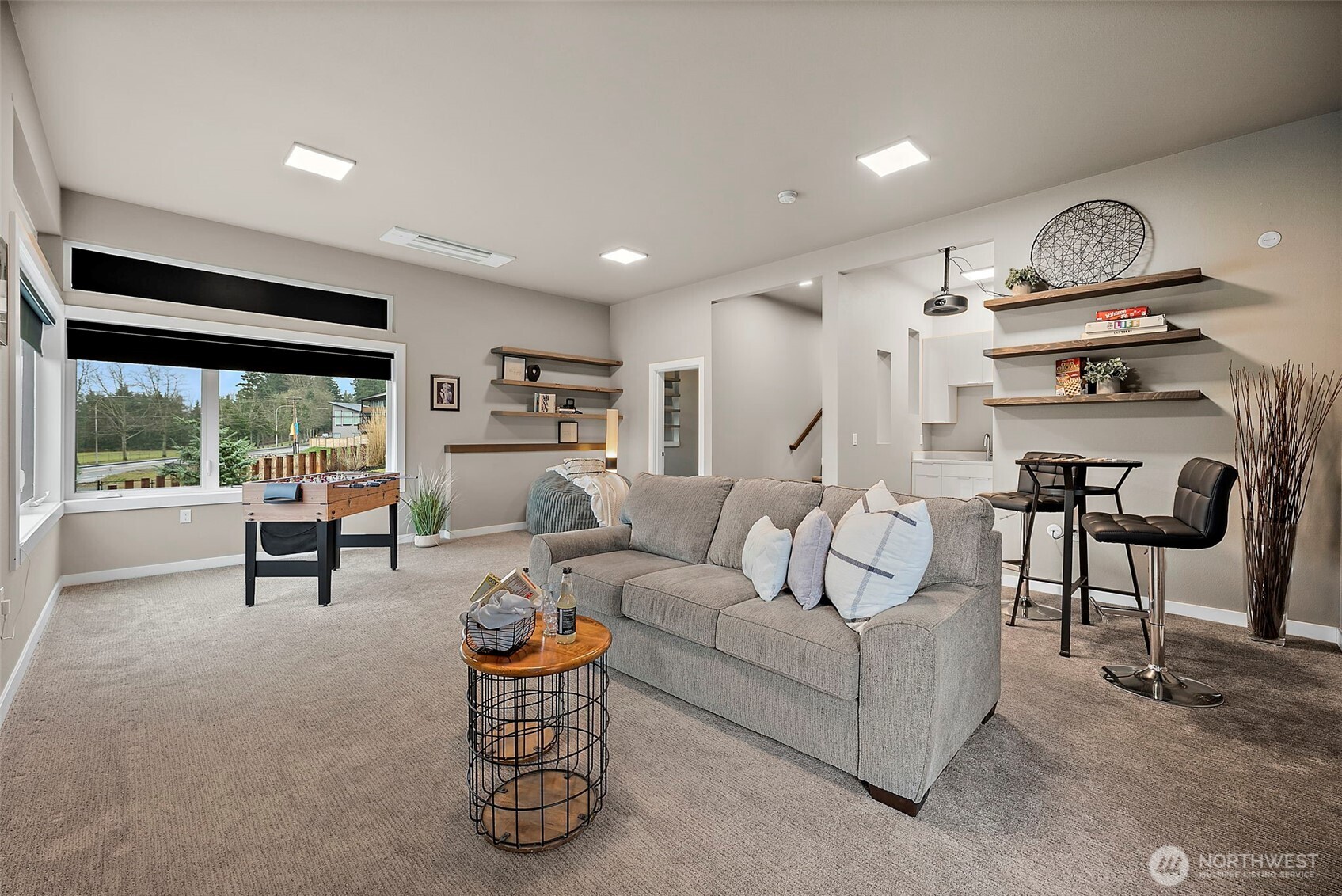 Spacious lower level entertainment room in this River Rock home in Auburn featuring a projector, large screen, wet bar, and comfortable seating areas. With direct patio access, this versatile rec room is designed for movie nights, hosting guests, and seamless indoor outdoor entertaining.
