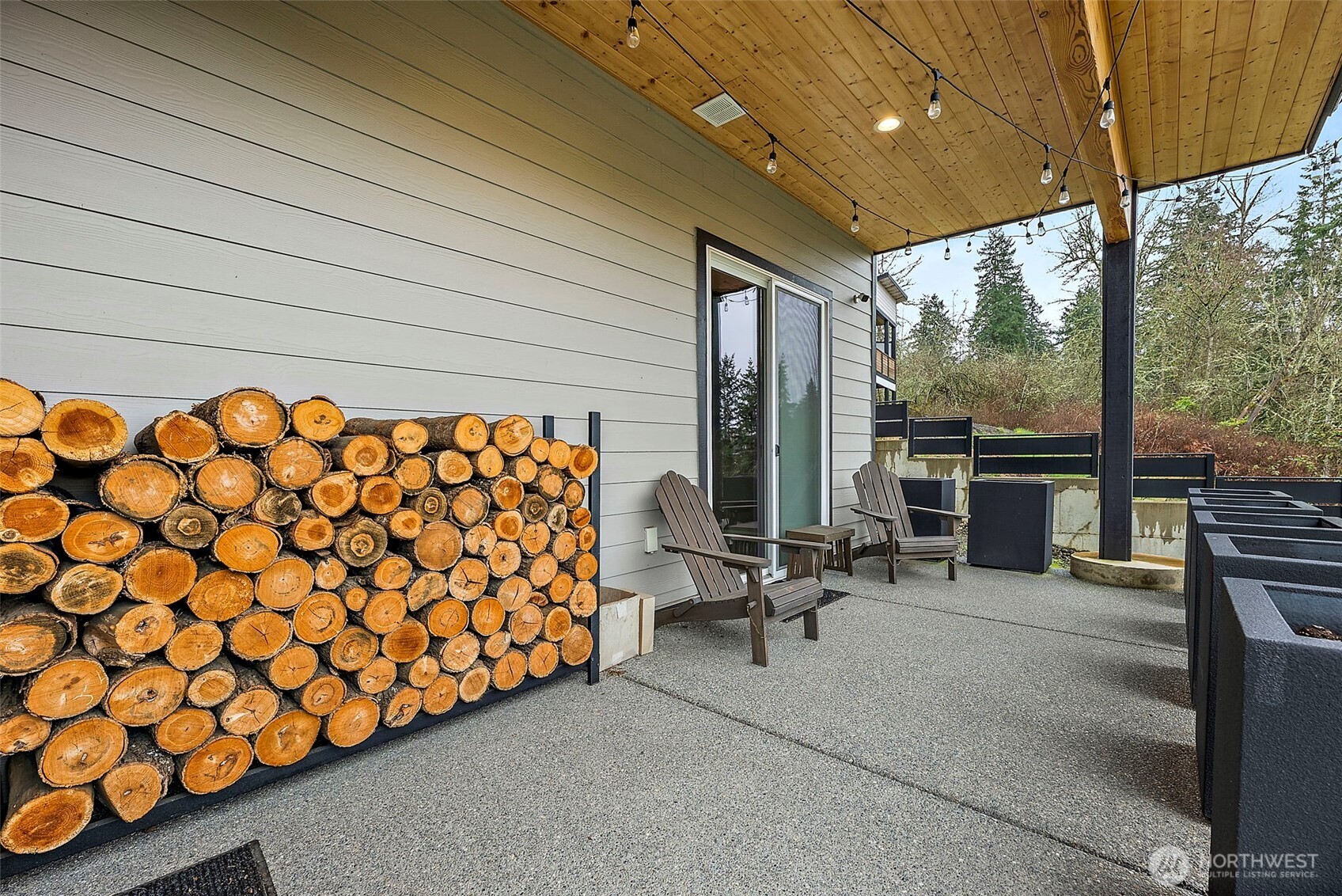 Covered back patio in this River Rock home in Auburn features a spacious outdoor seating area with wood ceiling accents and lighting, creating a comfortable space for relaxing or entertaining while enjoying the peaceful backyard setting.