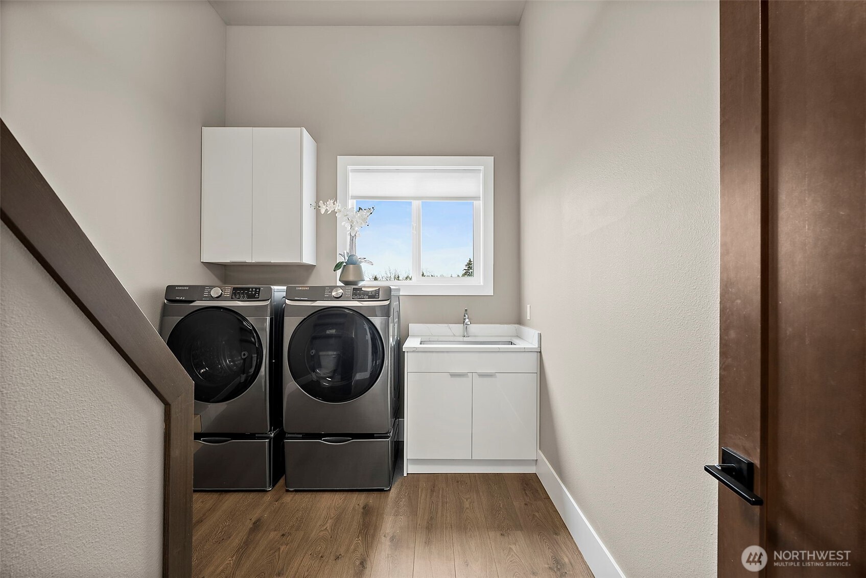 Laundry area in this River Rock home features a dedicated space with washer and dryer, upper cabinetry, and natural light from the window. The clean layout and built in storage create a practical and convenient laundry setup for everyday living.