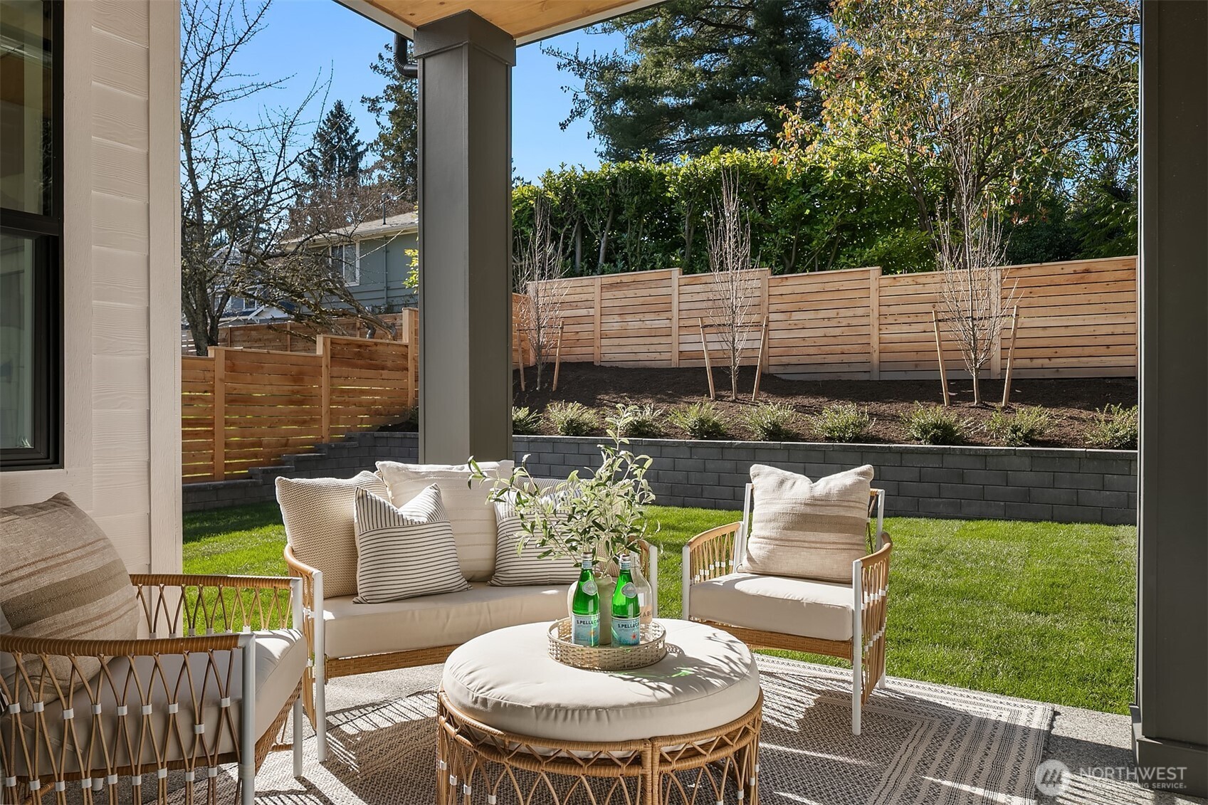 A covered outdoor patio with mounted heater and integrated ceiling speakers extends the living space outdoors, overlooking a fully fenced and beautifully landscaped yard.