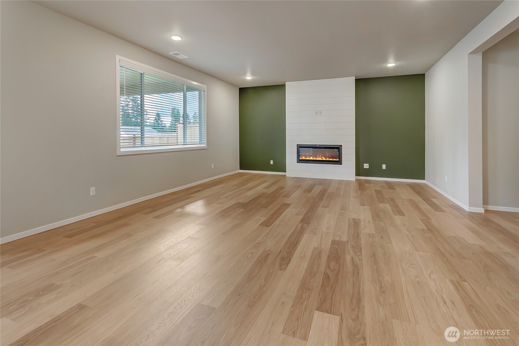 This spacious family room features oversized windows that fill the space with natural light, 1/2" laminate flooring throughout the main level, and a sleek modern linear fireplace for added warmth and style. Its open layout and generous size make it perfect for everyday living and effortless entertaining.