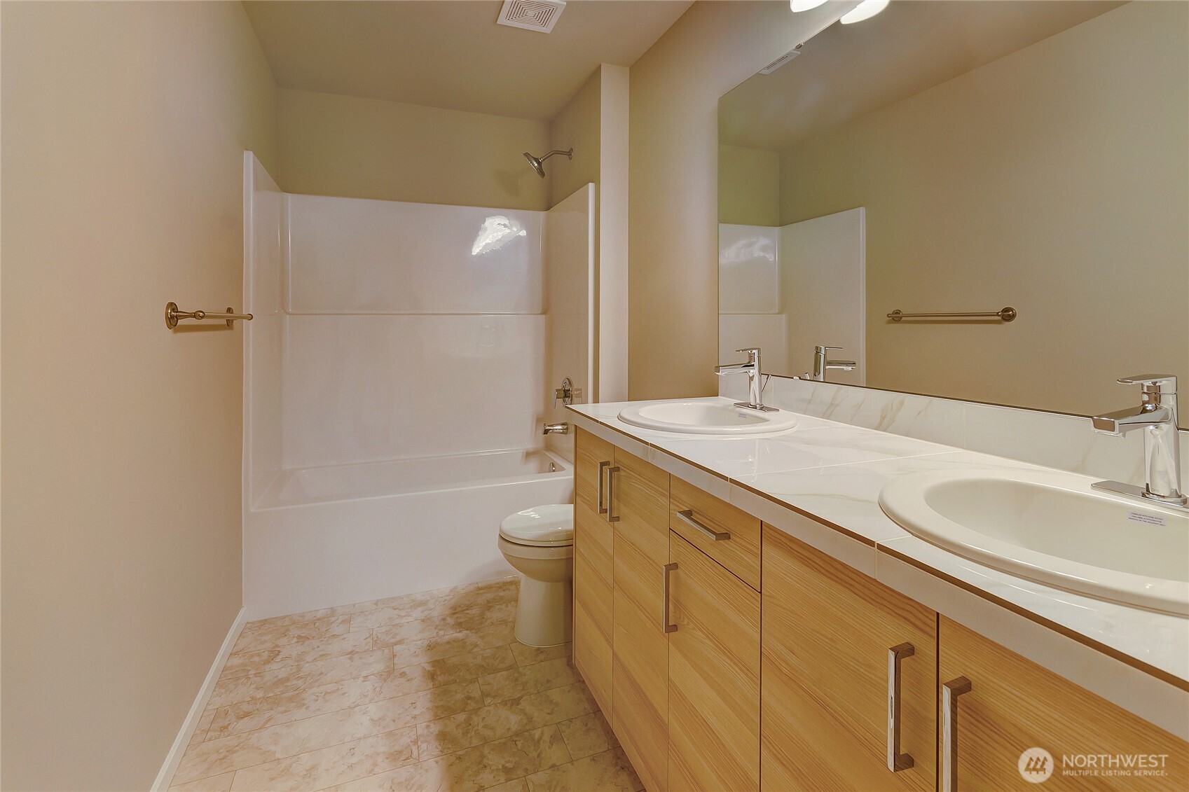 This expansive primary bathroom features a dual-sink vanity with a large mirror, a versatile tub-shower combo, and a spacious layout that enhances comfort and ease. With its clean design and thoughtful finishes, it offers a practical yet luxurious retreat within the home.