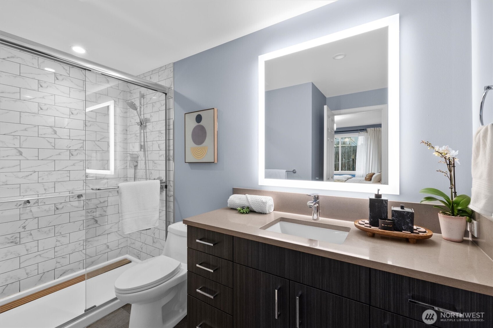 Spacious tiled shower with LED mirror.