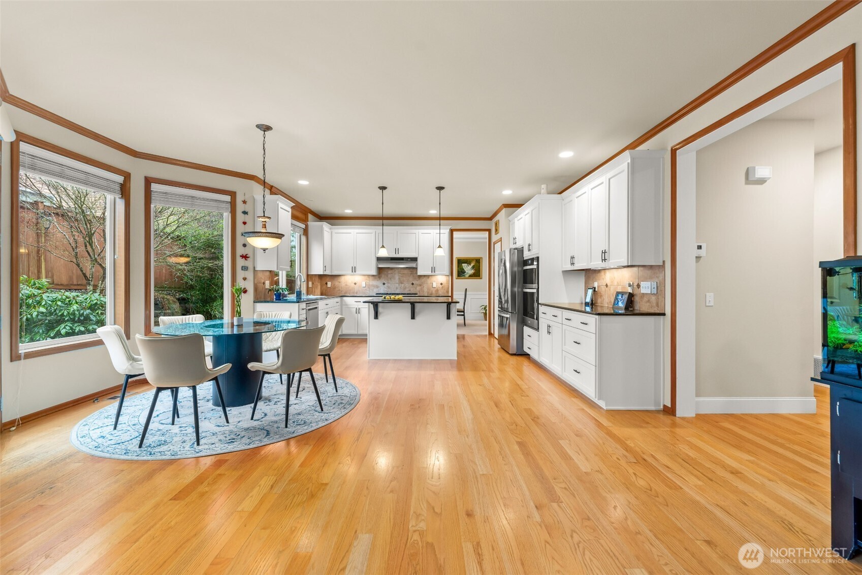 Chef's kitchen with a picture window, ample amount of quality cabinets, full backsplash, new stainless steel appliances, granite countertops, and island extends to a sun filled breakfast nook