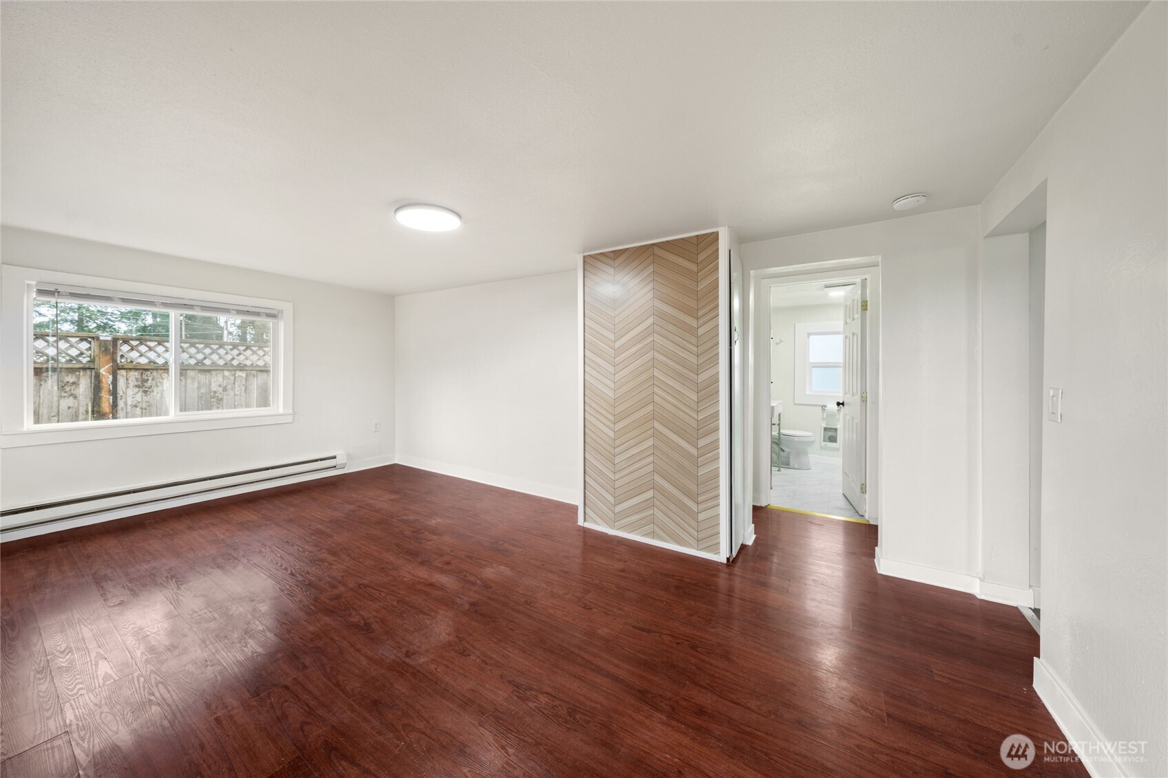 This bright and airy room features spacious dimensions, abundant natural light through large windows, and beautiful hardwood flooring.
