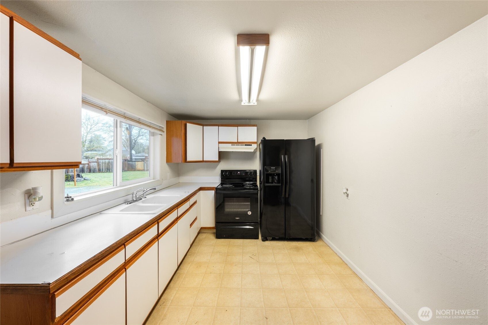 Bright and functional kitchenwith amplecabinetry, generous counter space, and window with backyard outlook