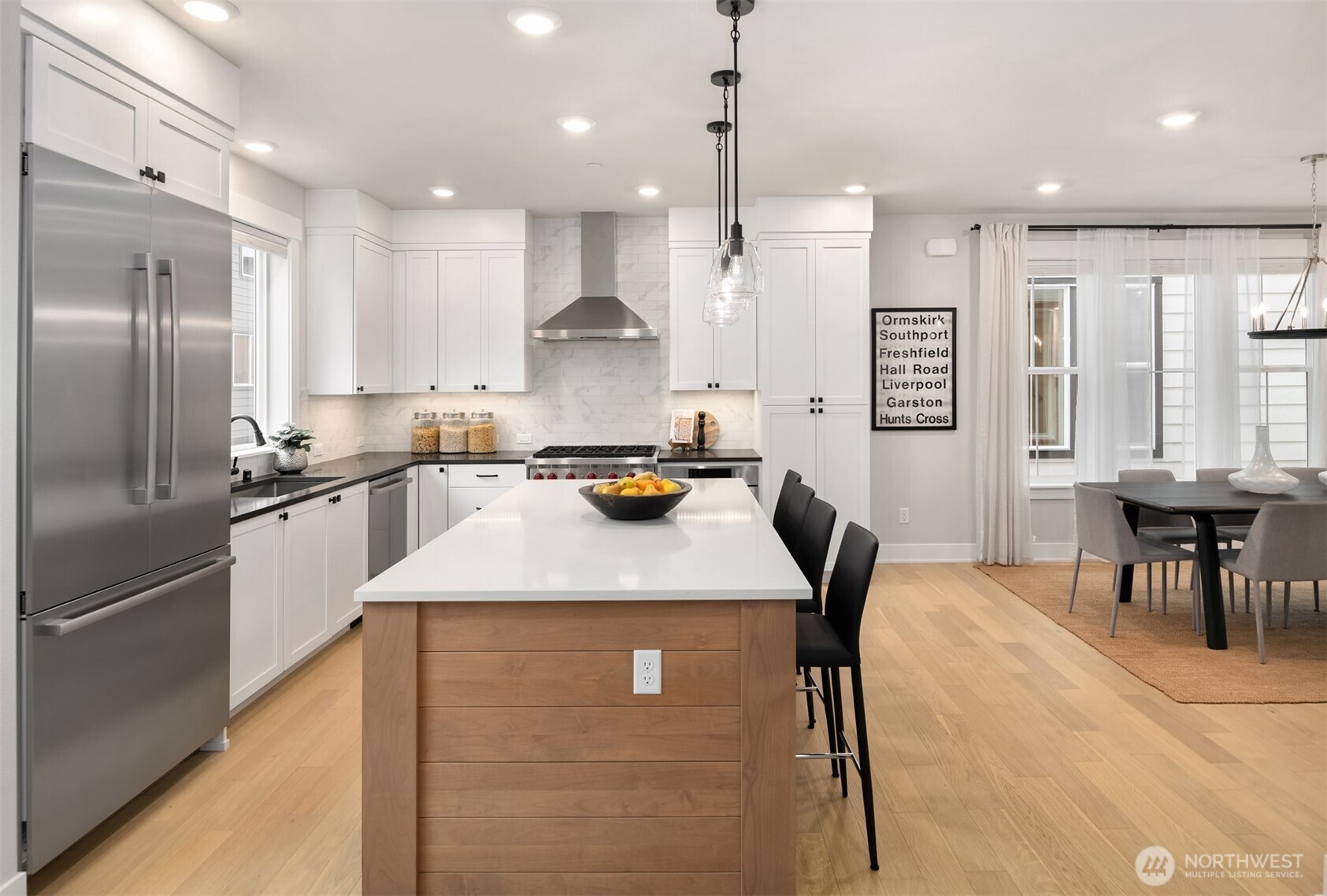 Designer pendant lighting and clean white cabinetry complement the kitchen’s modern farmhouse aesthetic.