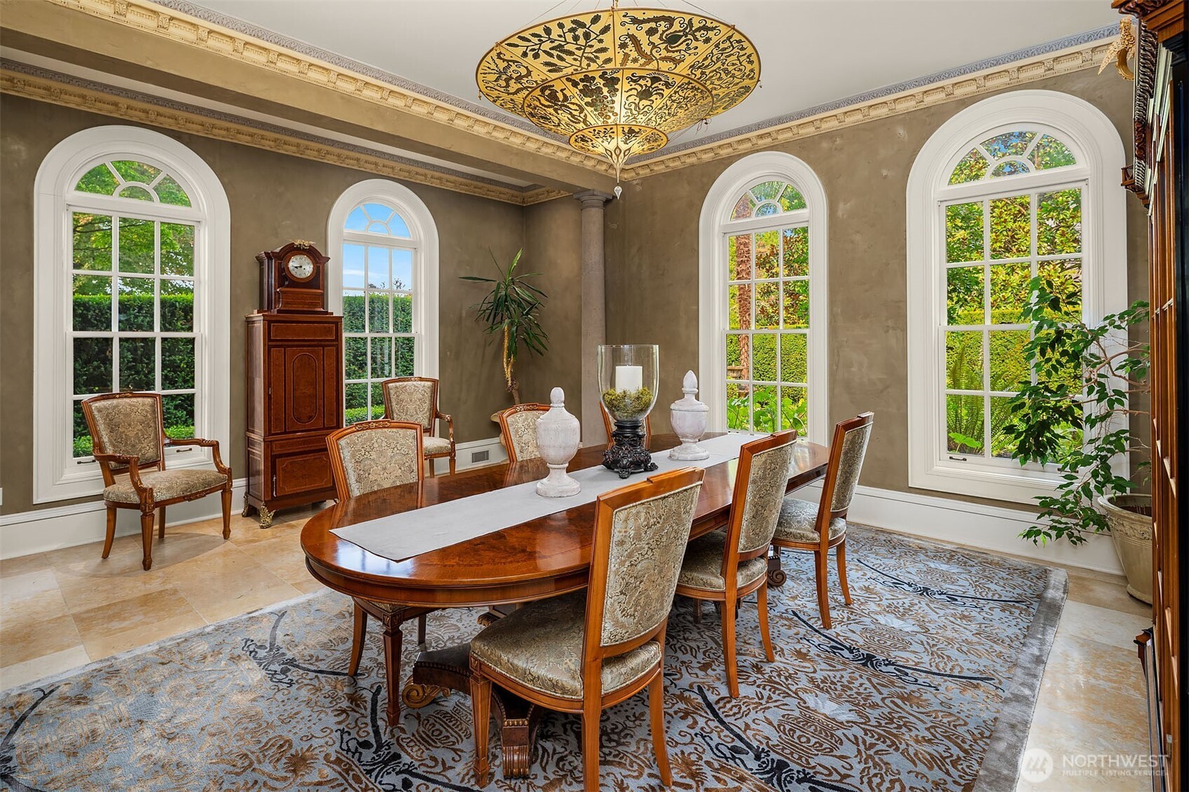 Gracious dining room with gorgeous silk Fortuny ceiling lamp and classic windows framing lush gardens and outdoor spaces.