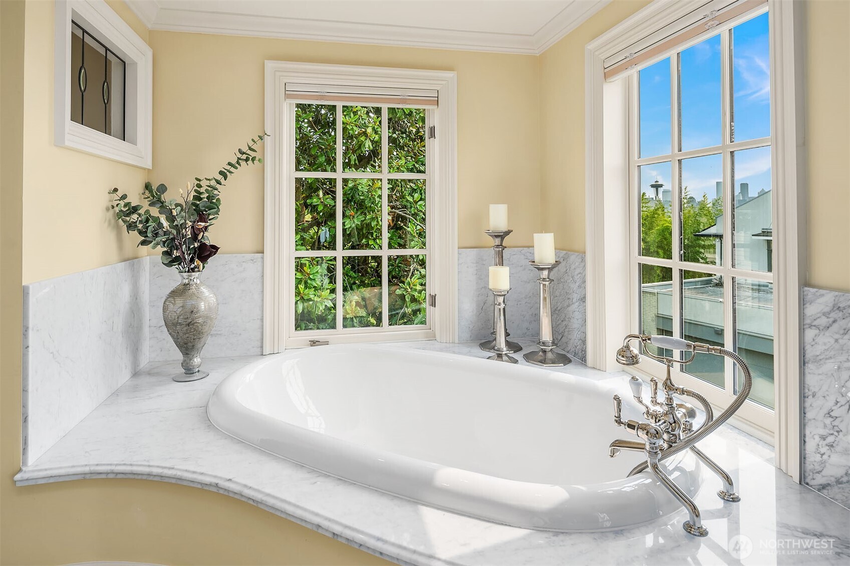 Fabulous soaking tub with handheld shower and Carrara marble surround – classic windows frame a view of the Space Needle.