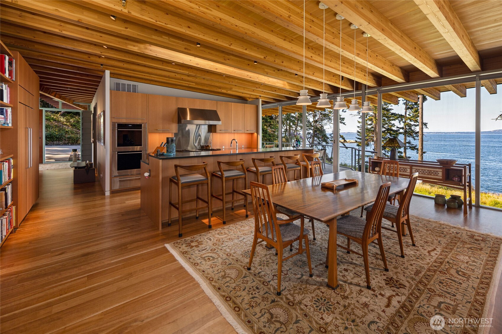 The open great room seamlessly connects kitchen, dining, and living spaces, all oriented toward expansive west-facing water views and breathtaking San Juan Island sunsets.