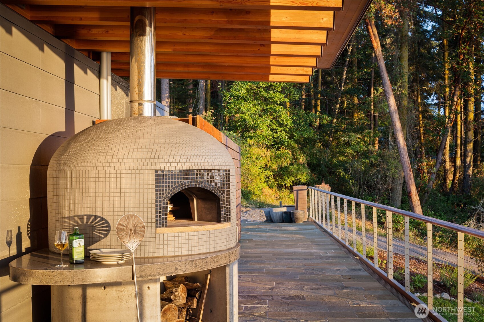 The outdoor entertaining terrace features a custom wood-fired pizza oven, perfect for gatherings and alfresco dining while enjoying the serene setting of this luxury waterfront estate on San Juan Island.